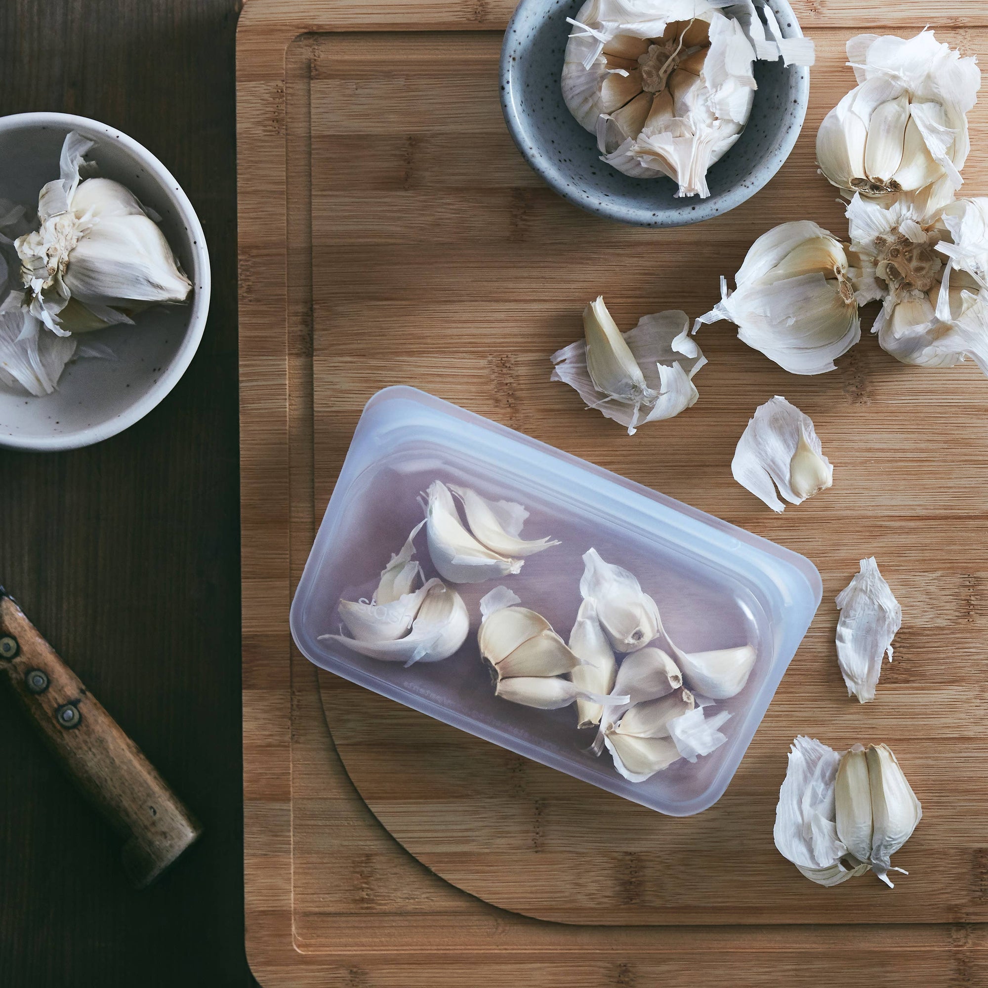 Stasher snack size reusable silicone storage bag with clear body and orange seal for snacks or small items.