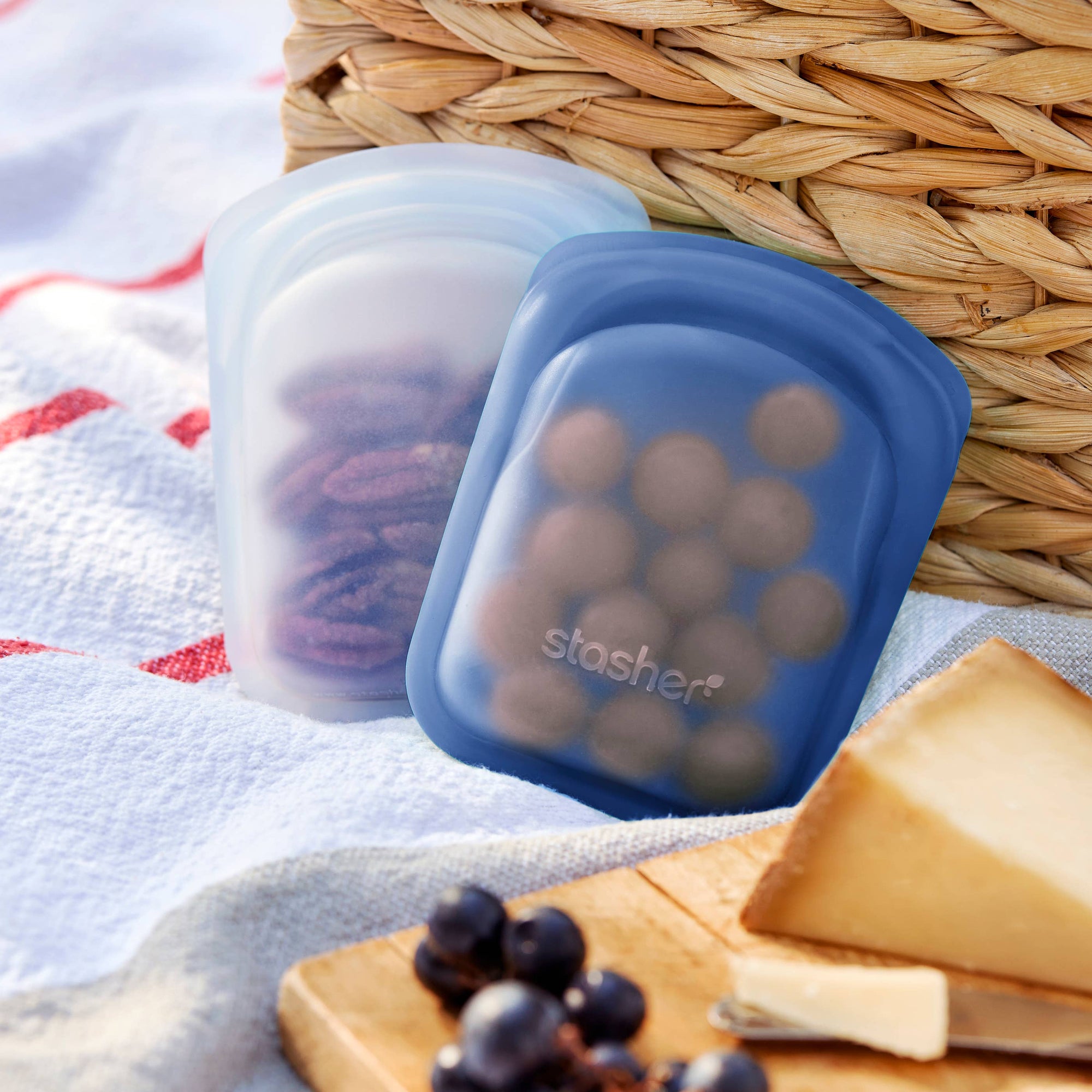 Two reusable Stasher silicone storage bags from the Stasher Pocket 2-Pack set, shown with transparent and colorful designs.
