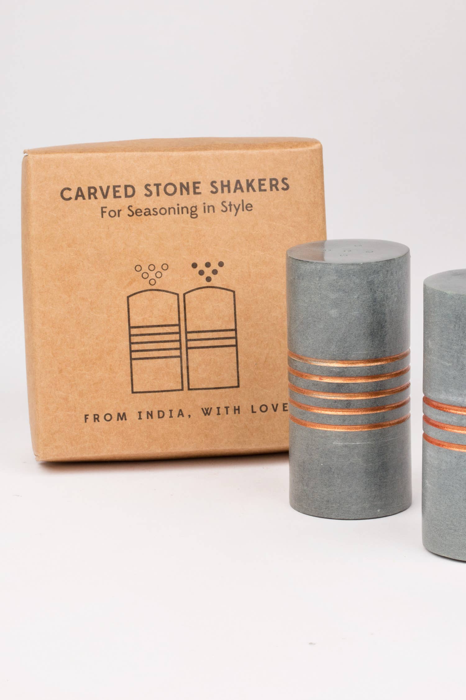 Salt and pepper stone shakers by Ten Thousand Villages, with textured stone surfaces and classic round shape.