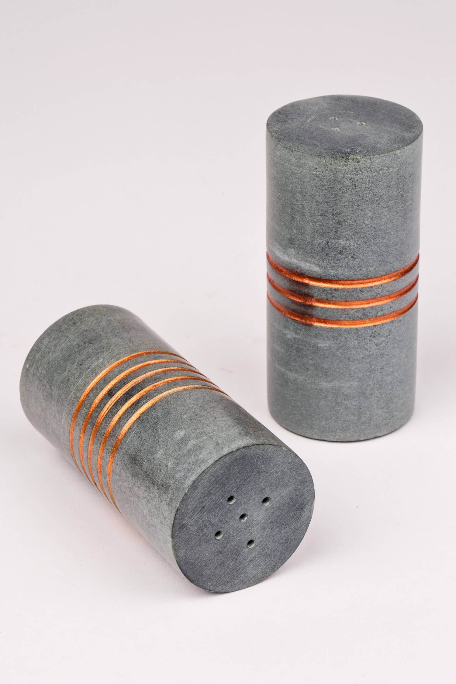 Salt and pepper stone shakers by Ten Thousand Villages, handcrafted with textured stone surfaces and classic design.