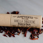 Juniperseed Mercantile Lip Balms displayed with natural packaging and ingredients on a neutral background.
