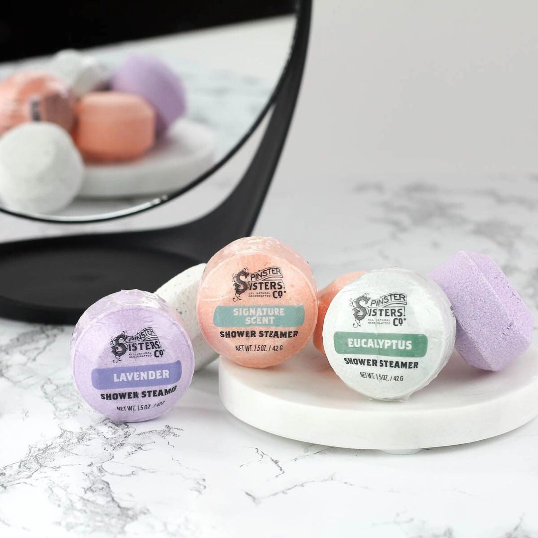 Group of Spinster Sisters shower steamers in various shapes and colors, designed to create aromatic steam in the shower.
